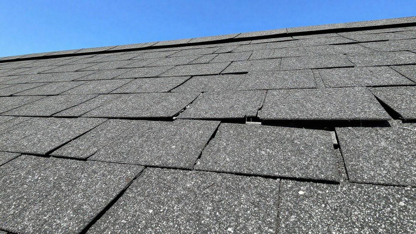 Damaged asphalt shingle roof with missing pieces.